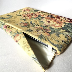 Könnte beinhalten: Eine gelbe Laptoptasche mit Blumendruck und Reißverschluss. Die Tasche ist aus Gobelin-Stoff mit einem Blumendesign in den Farben Gelb, Grün, Rot und Braun.