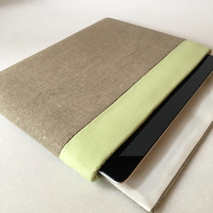 May include: A brown linen laptop sleeve with a light green stripe. The sleeve is open and a black tablet is inside.