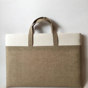 May include: A brown and white linen tote bag with two handles. The bag has a brown bottom and a white top.