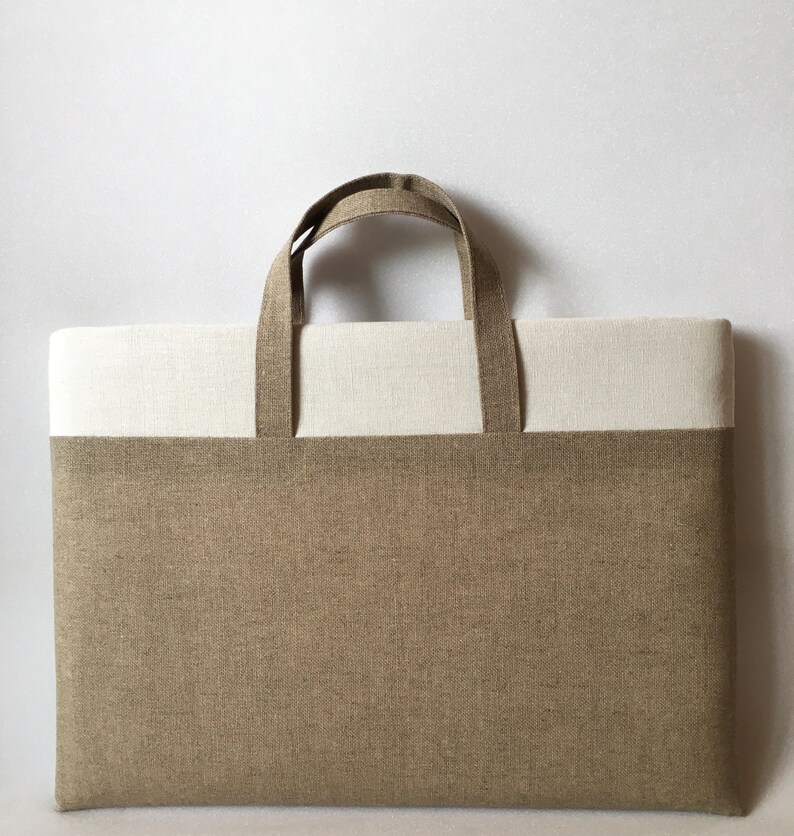 May include: A brown and white linen tote bag with two handles. The bag has a brown bottom and a white top.