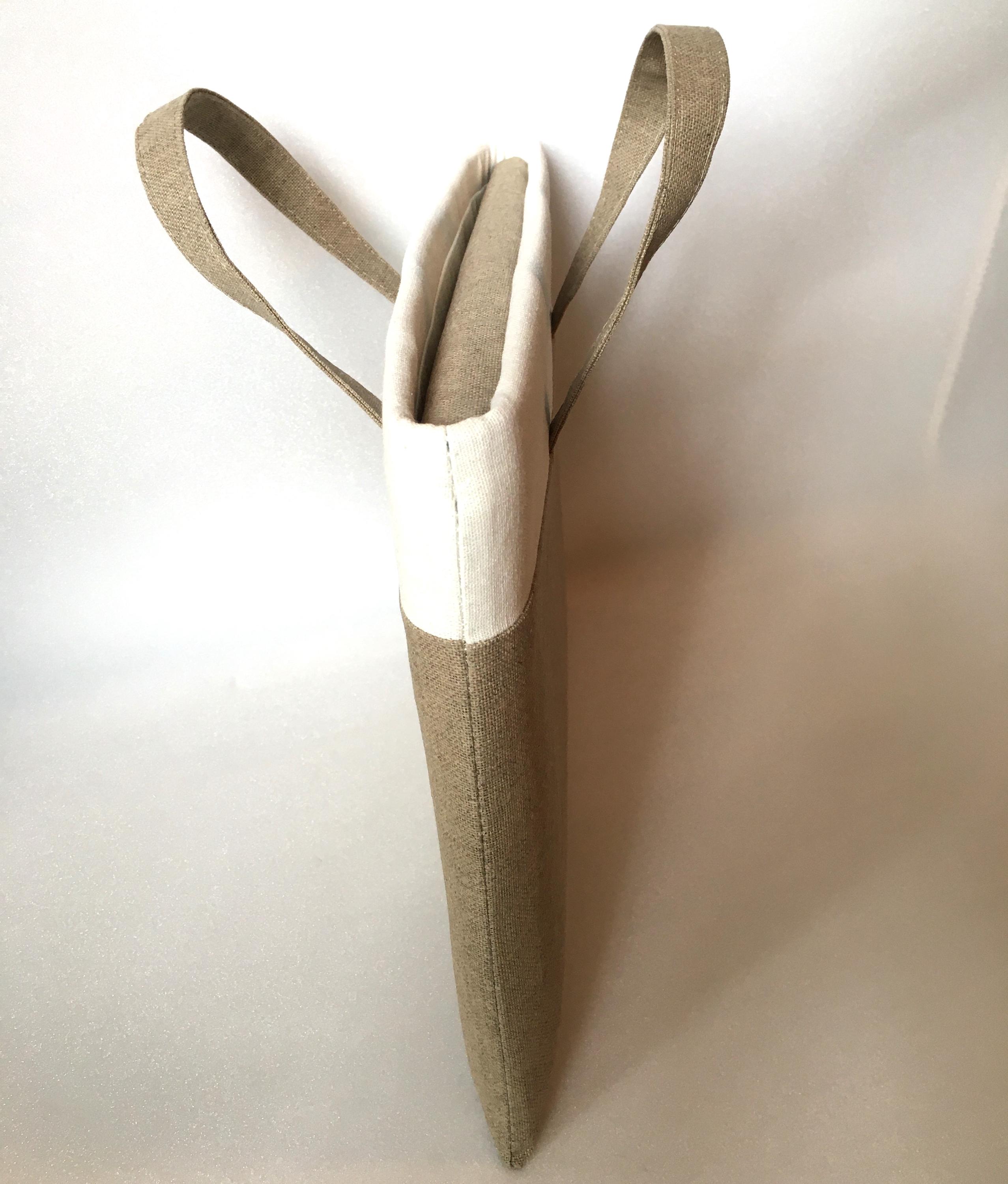 May include: A beige and white linen tote bag with two handles. The bag is made of a natural fabric and has a simple, elegant design.