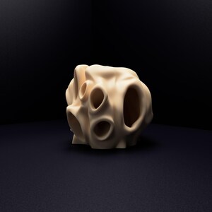 May include: A beige, organic-shaped sculpture with a smooth, matte surface. The object features multiple hollow, rounded openings of varying sizes distributed across its irregular, porous structure, creating a complex, cavernous appearance.