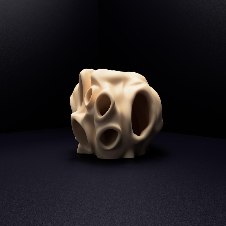 May include: A beige, organic-shaped sculpture with a smooth, matte surface. The object features multiple hollow, rounded openings of varying sizes distributed across its irregular, porous structure, creating a complex, cavernous appearance.