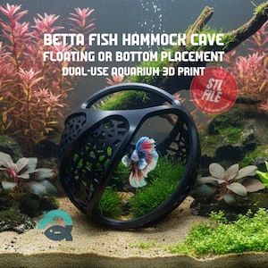 Può includere: Una grotta ad amaca per pesci Betta, sferica e nera, con un design a traliccio decorativo. Il testo sull'immagine recita "BETTA FISH HAMMOCK CAVE FLOATING OR BOTTOM PLACEMENT DUAL-USE AQUARIUM 3D PRINT". Un colorato pesce Betta nuota all'interno.