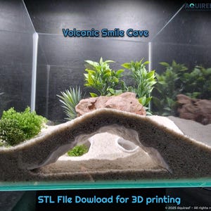 Peut inclure: Une grotte en forme de sourire imprimée en 3D, de couleur blanche, conçue pour être utilisée dans un aquarium. La grotte est placée sur un lit de sable blanc avec des plantes vertes en arrière-plan. Le texte "Volcanic Smile Cave" et "STL File Download for 3D printing" est visible sur l'image.