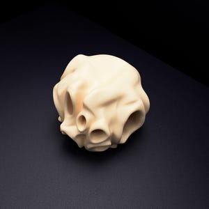 May include: A cream-coloured, spherical object with a smooth, matte finish and multiple hollow, circular openings distributed across its surface. The form features organic, undulating folds and curves that create a complex, three-dimensional structure.