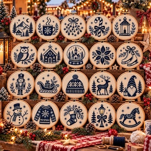 Peut inclure: Une collection de vingt tambours à broder circulaires en bois présentant des motifs de fêtes brodés en bleu foncé sur tissu crème, incluant un casse-noisette, un bonhomme de neige, un renne et divers motifs hivernaux sur une étagère.