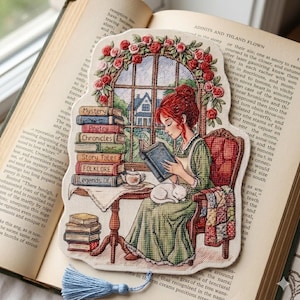Peut inclure: Un marque-page au point de croix représentant une personne lisant dans un fauteuil avec un chat, entourée de piles de livres intitulés Mystery, Poetry, Chronicles, Story Tales, Folklore et Legends Of, sous une fenêtre ornée de roses rouges.