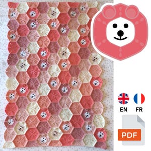 Peut inclure: Une couverture au crochet faite à la main avec un motif en nid d'abeille et des visages de lion dans les tons de rose, pêche et crème. La couverture est en fil doux et a un aspect texturé. Le design comprend un logo de lion et le texte "EN" et "FR".