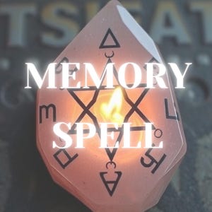 May include: A pink, multi-sided, crystal-like candle with a flame burning inside. The candle has black markings and the words "MEMORY SPELL" written on it.