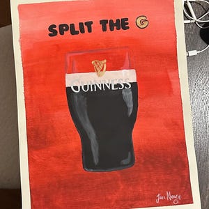 以下が含まれることがあります： 赤い背景に黒い文字で「SPLIT THE G」と書かれています。テキストの隣には金色の文字「G」があります。画像の中央には、ギネスビールのジョッキの白黒のイラストがあります。ジョッキには「GUINNESS」の文字が印刷されています。画像は右下に「Jace Neary」の署名があります。