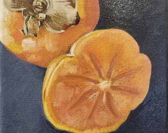 May include: Two ripe persimmons, one whole and one cut in half, are displayed on a dark blue background. The cut persimmon reveals its orange flesh and star-shaped core.