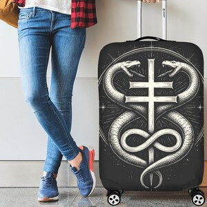 May include: Black suitcase cover with a detailed illustration of two snakes coiled around a cross. The snakes are white, and the cross is a light grey colour, set against a starburst design on a black background.