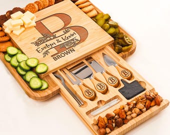 May include: Personalized bamboo cheese board with a drawer for cheese knives. The board features a floral design and the text "Evelyn & Kevin BROWN".