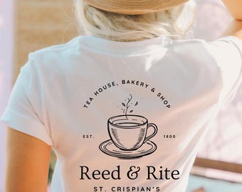 May include: White t-shirt featuring a black illustration of a teacup and saucer, with steam rising. The text above reads "TEA HOUSE, BAKERY & SHOP." Below the graphic, the text reads "Reed & Rite ST. CRISPIAN'S."