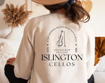Könnte beinhalten: Sandfarbenes Sweatshirt mit Cello-Grafik und dem Text "Every morning should begin with a cello." Das Design enthält die Wörter "Stonecrop England" und "Islington Cellos."