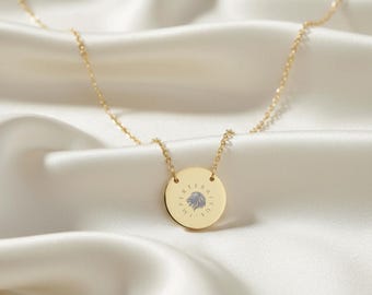 May include: A gold-toned necklace featuring a circular pendant with a central lion head engraving and the text IMPERRITUS inscribed in a circular pattern around the lion. The pendant is suspended from a delicate gold-toned chain link necklace.