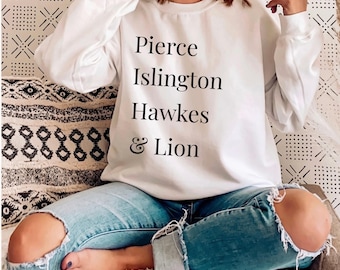 Könnte beinhalten: Ein weißes langärmeliges Sweatshirt mit Rundhalsausschnitt und schwarzem Textaufdruck auf der Vorderseite, der Pierce, Islington, Hawkes, & Lion lautet. Das Kleidungsstück hat eine Standardpassform mit gerippten Bündchen und Halsausschnitt, kombiniert mit einer blauen Jeans.