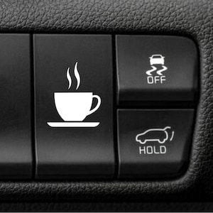May include: A close-up of a black car dashboard with white icons. The image features a coffee cup icon with steam, a car with squiggly lines and the word OFF, and a car with the word HOLD.