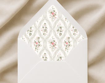 May include: A white envelope with a floral patterned interior. The interior design features a repeating pattern of pink roses and green leaves on a light gray background. The envelope is open, revealing the decorative lining.
