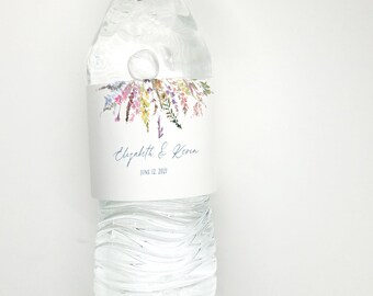 May include: A clear plastic water bottle with a white label featuring a watercolor floral design and the text "Elizabeth & Kevin June 12, 2023".