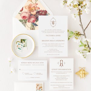 May include: A wedding invitation suite with a floral design on the envelope. The invitation card features a gold monogram with the initials "VA" and the text "MR. AND MRS. JEFFREY WRIGHT REQUEST THE PLEASURE OF YOUR COMPANY AT THE MARRIAGE OF THEIR DAUGHTER VICTORIA ANNE TO BRADEN MILO ANDREWS SATURDAY, THE TWENTY-FIRST OF AUGUST TWO THOUSAND TWENTY-FIVE AT HALF PAST FOUR IN THE AFTERNOON COOPER HOUSE 4011 DICK POND ROAD MYRTLE BEACH, SOUTH CAROLINA RECEPTION TO FOLLOW". The RSVP card has a floral design and the text "KINDLY REPLY BY JULY 25TH WE HAVE RESERVED SEATS IN YOUR HONOR M ACCEPTS WITH PLEASURE DECLINES WITH REGRET NUMBER ATTENDING". The guest information card has a gold monogram with the initial "A" and the text "GUEST INFORMATION FOR YOUR CONVENIENCE, A BLOCK OF ROOMS HAS BEEN RESERVED AT STAYBRIDGE SUITE MYRTLE BEACH WEST, AN IHG HOTEL 811 FANTASY HARBOR BLVD MYRTLE BEACH, SC 29577 PLEASE MAKE YOUR RESERVATION BY JULY 15TH FOR MORE INFORMATION ABOUT OUR WEDDING, PLEASE VISIT: THEKNOT.COM/BLAKETOTSIEDALTAR".