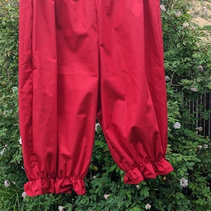 May include: Red cotton bloomers with a gathered elastic waistband and a ruffled hem.
