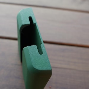 Op de afbeelding: Een matte bosgroene 3D-geprinte kunststof houder met een rechthoekige vorm en een verticale gleuf aan de bovenrand. Het object heeft een getextureerde oppervlakteafwerking en een holle binnenruimte ontworpen voor het vasthouden van een plat item.