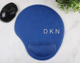 Könnte beinhalten: Blaues Leder-Mauspad mit einer Handballenauflage und den in Weiß gestickten Initialen "DKN".