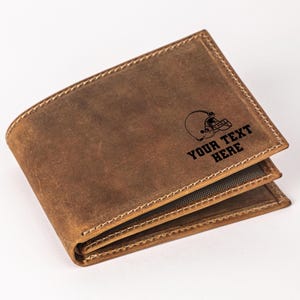 May include: A brown leather wallet with a football helmet design and the text "YOUR TEXT HERE" engraved on the front.