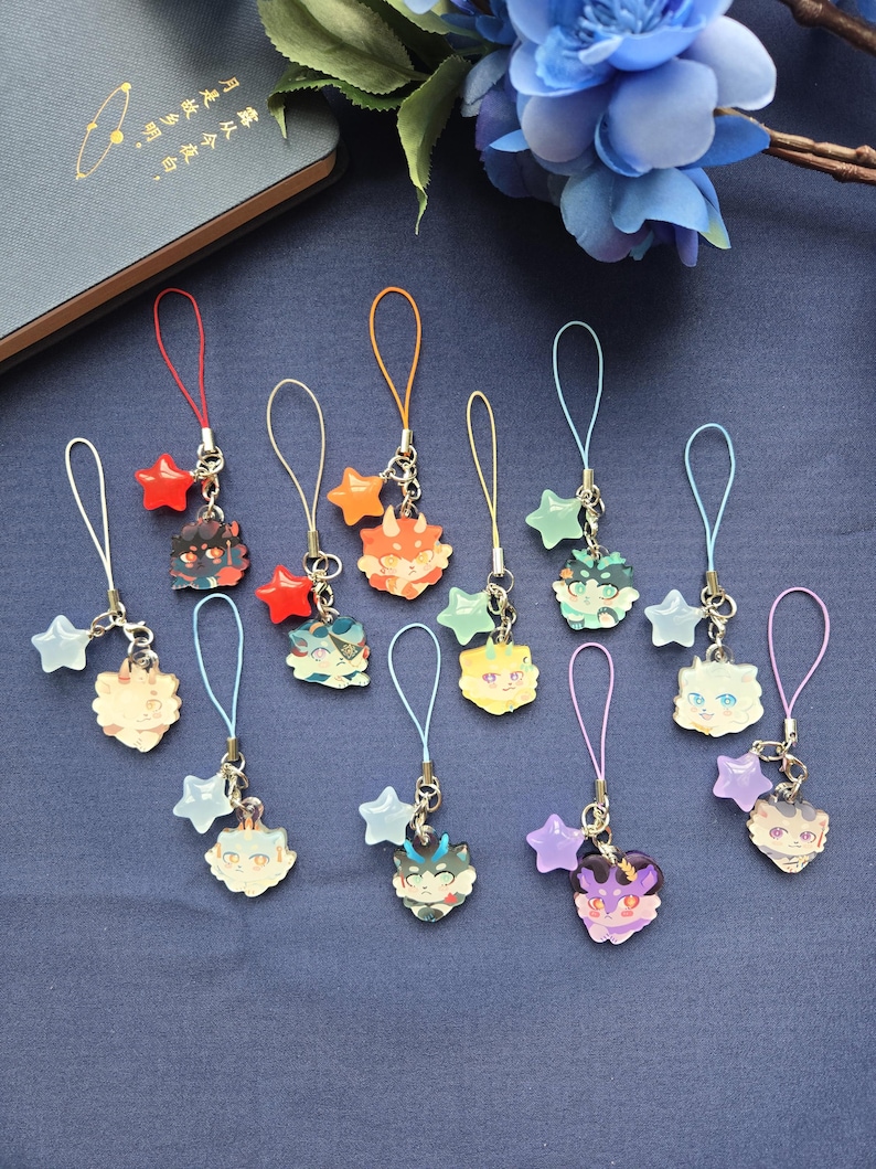 May include: A collection of colorful anime-style charms with various animal faces. Each charm is attached to a silver chain with a star-shaped accent and a loop for attachment. The charms are in shades of red, orange, green, blue, yellow, and purple.