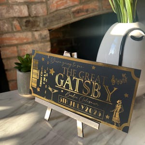 May include: A black and gold ticket with the text "You're going to see... The Great Gatsby" and "London Coliseum 5th July 2025".