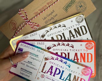 May include: A collection of Christmas-themed items. Includes a brown envelope with red and white twine, and three "Official Ticket to Lapland" boarding passes in gold, red, and iridescent colors. The tickets feature reindeer and snowflake designs.