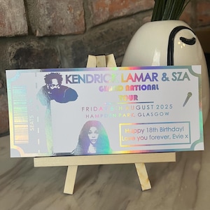 May include: A holographic ticket for a Kendrick Lamar and SZA concert. The ticket says "Grand National Tour" and lists the date as "Friday 3rd August 2025" and the location as "Hampden Park Glasgow". The ticket also has a birthday message that says "Happy 18th Birthday! Love you forever, Evie x".