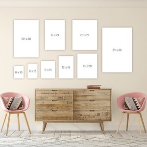May include: A gallery wall with eight white picture frames of different sizes. The frames are hung on a light beige wall above a wooden dresser with two pink chairs. The frames are labeled with their dimensions in inches.