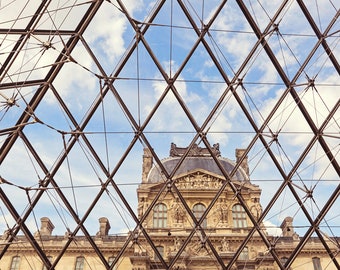 May include: A view of the Louvre Museum in Paris, France, through the glass pyramid. The pyramid is made of steel and glass and is a modern architectural masterpiece. The Louvre is one of the most famous museums in the world and is home to some of the most iconic works of art, including the Mona Lisa.