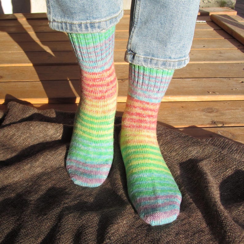 May include: A pair of colorful, striped socks in shades of blue, green, yellow, and red. The socks are worn with blue jeans. The socks are made of a soft, knitted material.