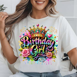 May include: White t-shirt with a colorful graphic design featuring a crown, the words "Birthday Girl", and a rose. The design has a sparkly, glittery effect.