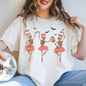 Cute skeleton ballerina in pink tutu dancing with pumpkins