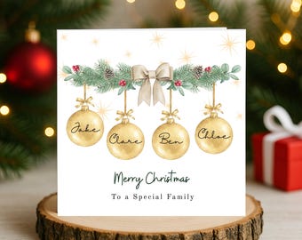 May include: A Christmas card with gold ornaments, each bearing a name: Jake, Clare, Ben, and Chloe. The card features a festive garland with a bow, pine needles, and berries. The text reads "Merry Christmas To a Special Family."