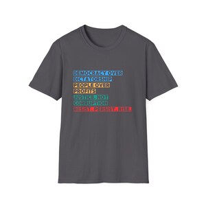 May include: Dark gray t-shirt with a white, blue, yellow, and red slogan that reads "Democracy Over Dictatorship, People Over Profits, Justice, Not Corruption, Resist. Persist. Rise."