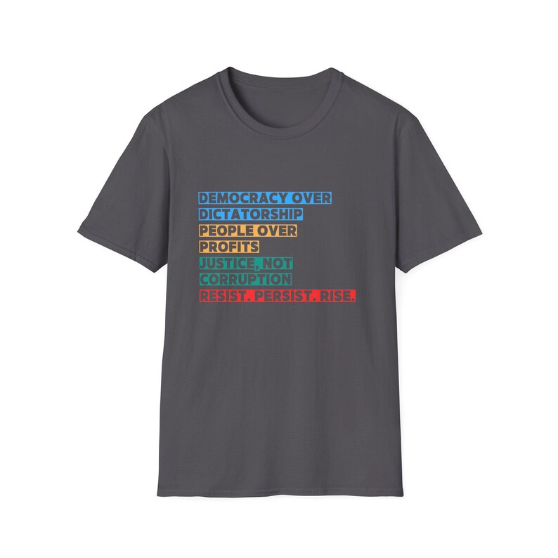 May include: Dark gray t-shirt with a white, blue, yellow, and red slogan that reads "Democracy Over Dictatorship, People Over Profits, Justice, Not Corruption, Resist. Persist. Rise."