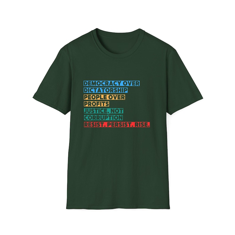 May include: A dark green t-shirt with a white, blue, yellow, orange, and red graphic print that reads "Democracy Over Dictatorship, People Over Profits, Justice, Not Corruption, Resist. Persist. Rise."