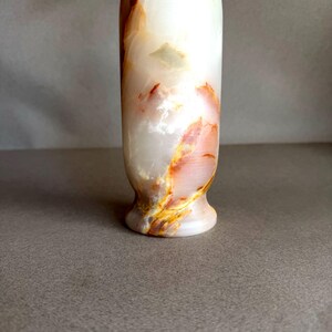 Pode incluir: Um vaso decorativo alto feito de &ocirc;nix branco com listras laranja e amarelo. O vaso tem uma base alargada e uma superf&iacute;cie lisa e polida. A pedra natural tem uma qualidade transl&uacute;cida.