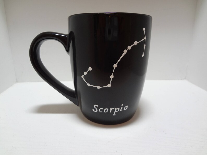 May include: Black ceramic mug with a white outline of the Scorpio constellation and the word "Scorpio" printed on the bottom.