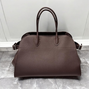 May include: A brown leather handbag with two top handles and a structured, slightly rounded shape.