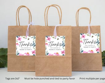 Peut inclure: Trois sacs en papier brun avec des poignées en ficelle blanche et des étiquettes de remerciement florales attachées. Les étiquettes mesurent 5x5 cm et présentent des fleurs roses, des feuilles vertes et des abeilles. Le texte sur les étiquettes indique "Merci d'être venu à la fête de NAME".