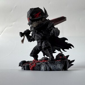 Puede incluir: Una figura negra de un guerrero con armadura, sosteniendo una gran espada roja. La figura tiene un casco con detalles rojos y una capa negra. La base es un terreno rocoso con detalles rojos.