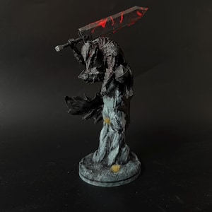 Puede incluir: Una figura detallada de un guerrero con armadura oscura sobre una base de piedra texturizada. La figura lleva una armadura negra dentada con detalles rojos y sostiene una espada masiva y desgastada sobre los hombros. La capa fluye detr&aacute;s.