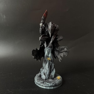 Puede incluir: Una figura oscura y texturizada de un caballero con armadura sobre una base rocosa. El caballero lleva un casco puntiagudo y una capa fluida, sosteniendo en alto un arma grande con hoja roja. La figura est&aacute; representada en negro y gris.